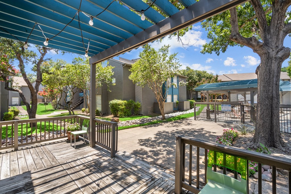 a patio with a blue awning and benches and trees in the background  at Vesper, Dallas