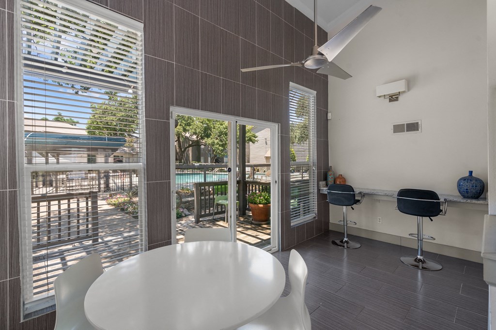 a dining area with a white table and chairs and a sliding glass door that leads to a a dining area with a white table and chairs and a sliding glass door that leads to a at Vesper, Dallas