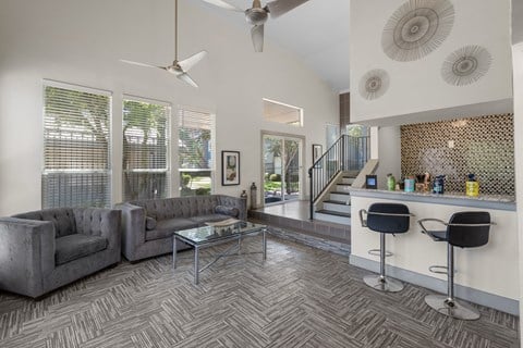 a living room with couches and a bar and a staircase