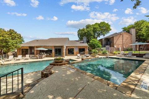 A pool surrounded by a patio and a house.