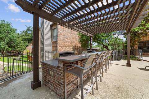 A patio with a table and chairs under a pergola.