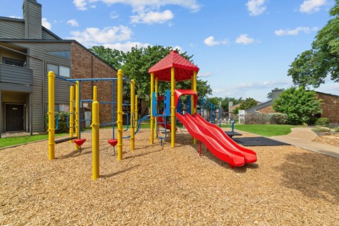 A playground with a red slide and yellow poles.