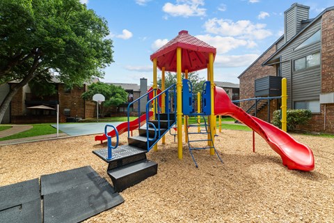 A playground with a red slide and a yellow and blue structure.