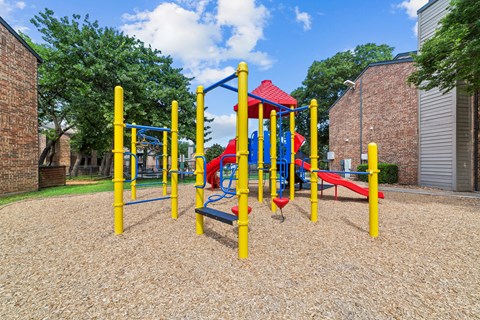 A playground with a red slide and yellow poles.