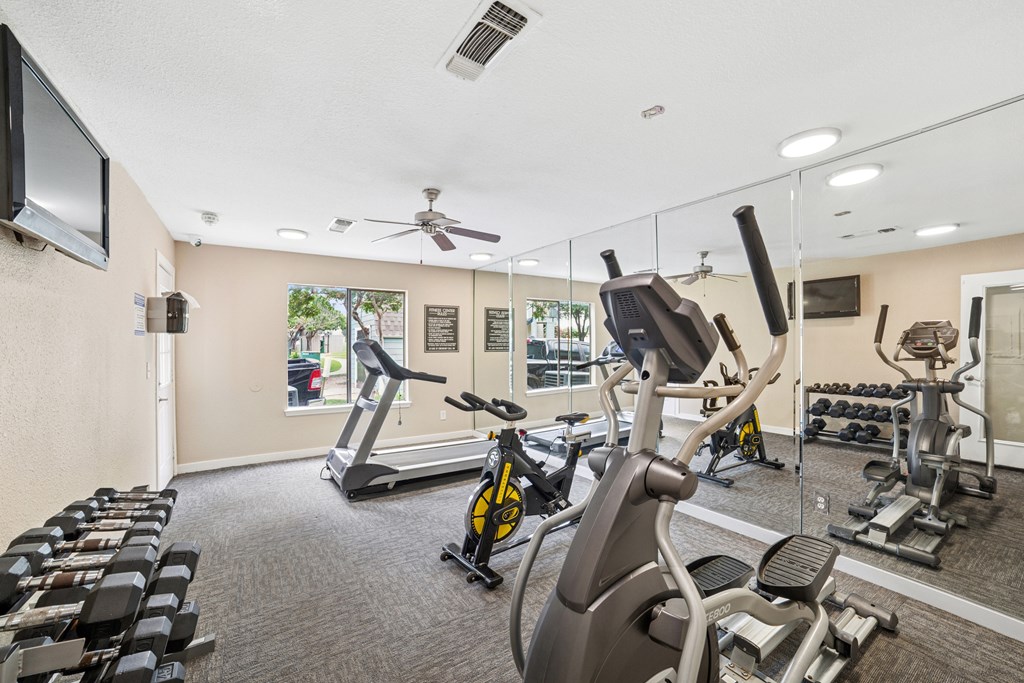 A gym with a variety of exercise equipment including treadmills, stationary bikes, and weight machines.