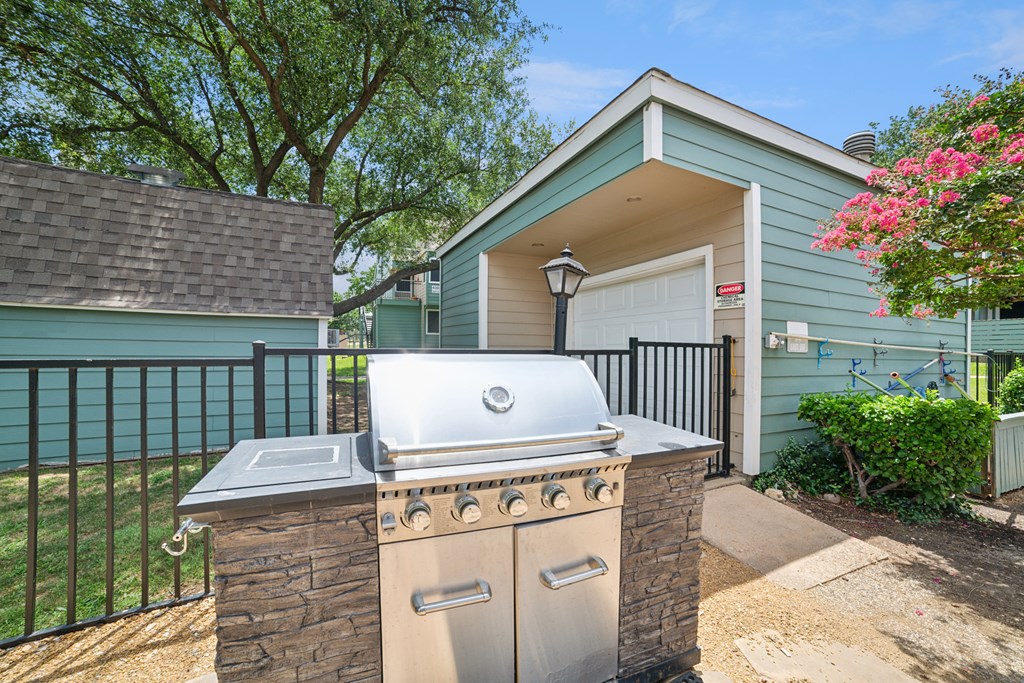 A house with a blue exterior has a silver grill on a stone pillar.