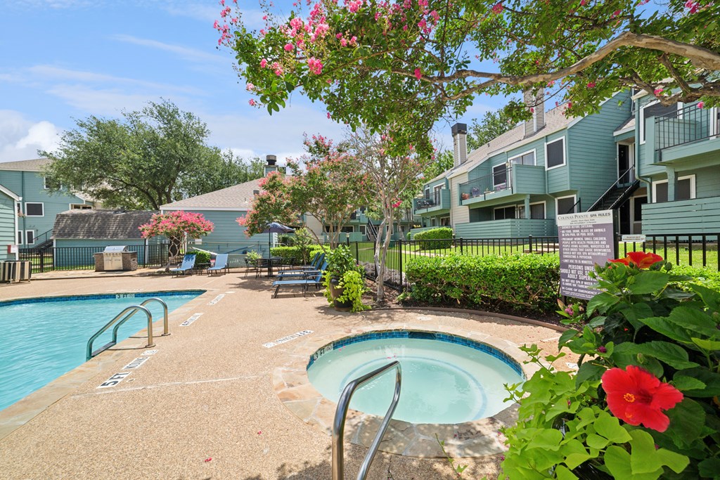 A pool surrounded by a green fence and flowers.