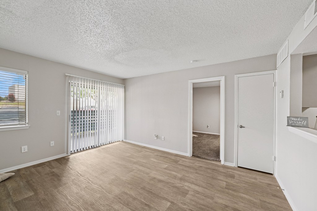 A spacious room with a sliding glass door and a wooden floor.