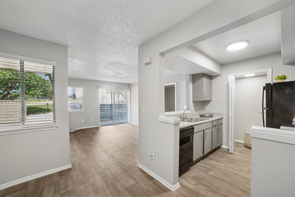 A kitchen with white cabinets and a black fridge.