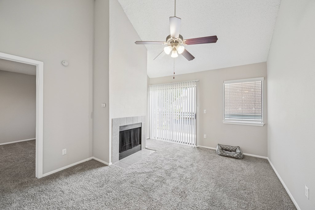 A spacious living room with a fireplace and a ceiling fan.