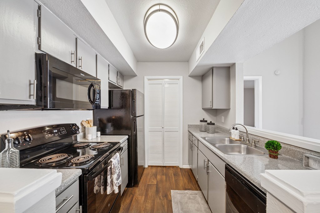 A modern kitchen with black appliances and white cabinets.