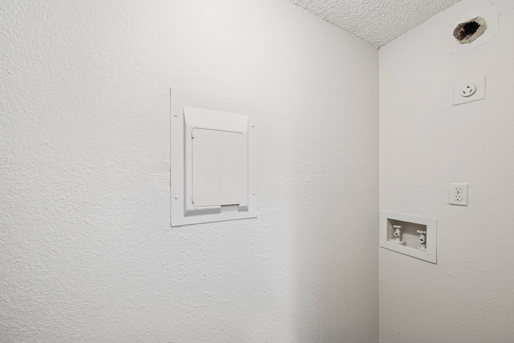 A white wall with a white electrical outlet and a white door.