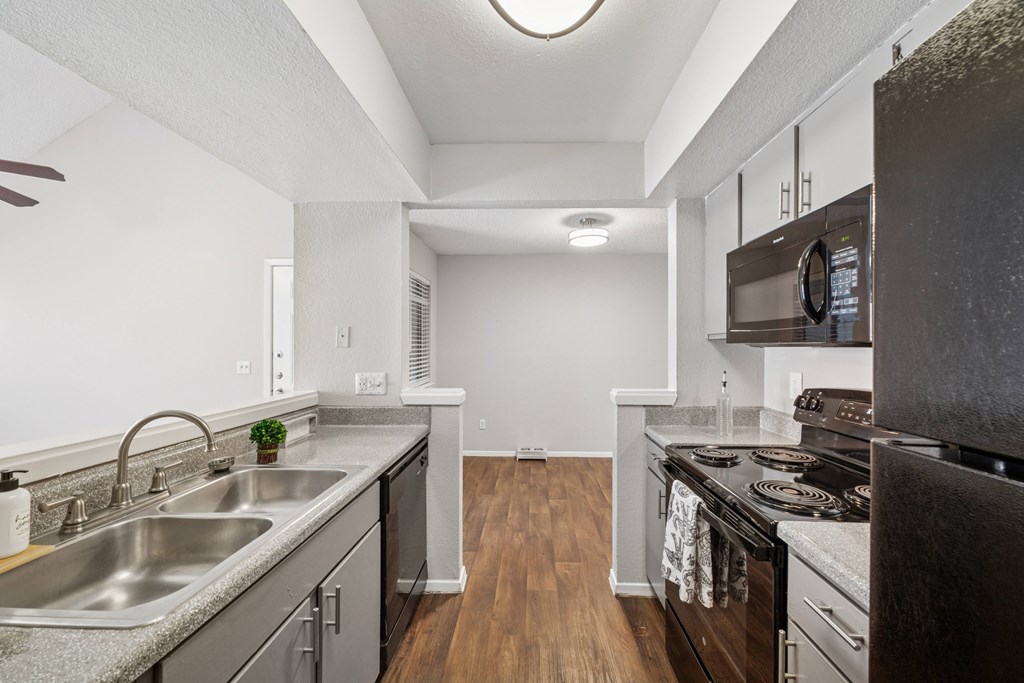 A kitchen with a stainless steel sink and black appliances.