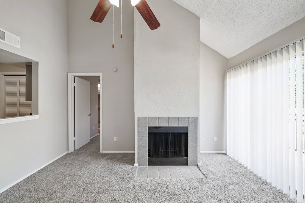 A living room with a fireplace and a ceiling fan.
