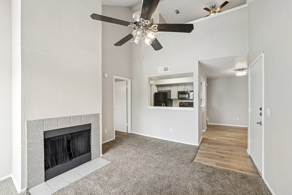 A living room with a fireplace and a ceiling fan.