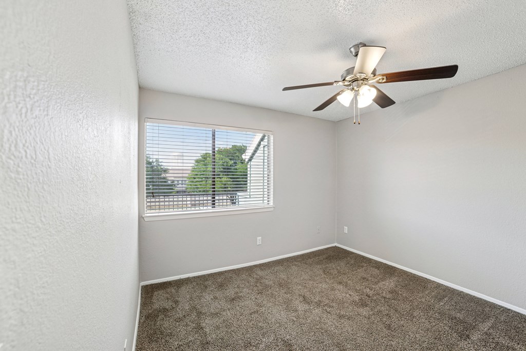 A room with a ceiling fan and a window with blinds.