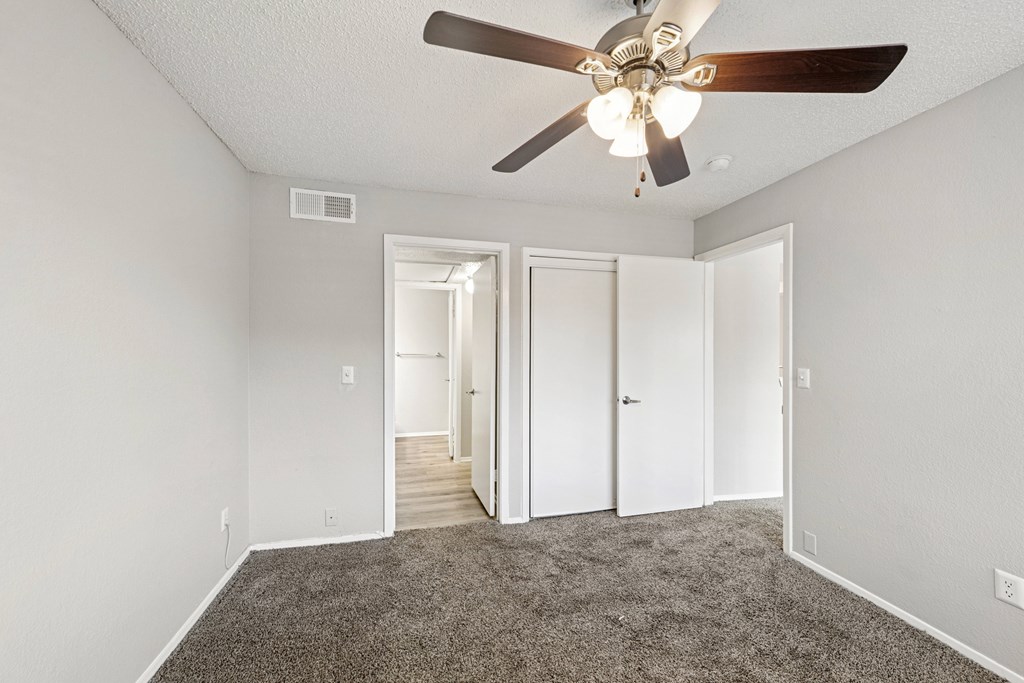 A room with a ceiling fan and carpeted floor.