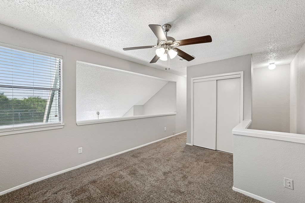 A room with a ceiling fan and carpeted floor.