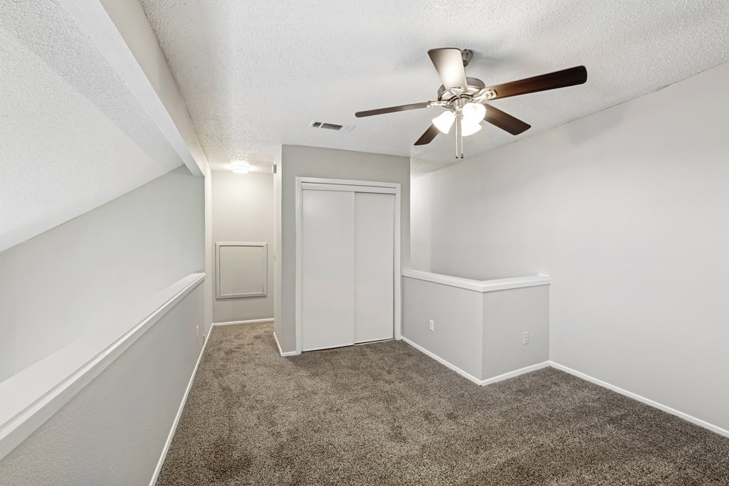 A room with a ceiling fan and carpeted floor.