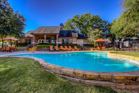 Resort style swimming pool with lounge chairs at Waters Edge Villas Apartments, Rowlett, TX