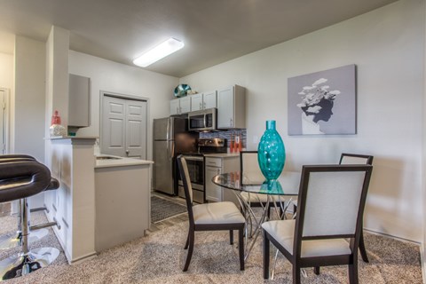 A kitchen area with a table and chairs.