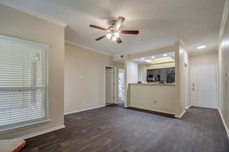 an empty living room with a ceiling fan and a kitchen
