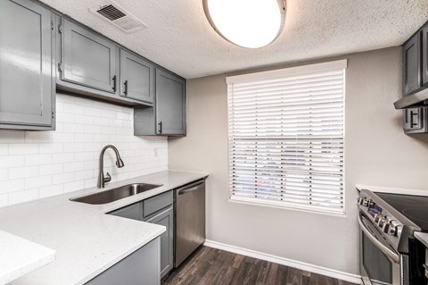 A kitchen with a white counter top and a stainless steel sink.
