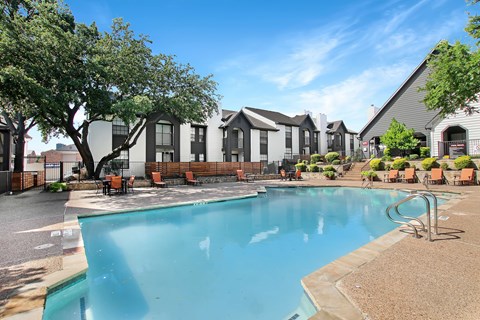 A swimming pool in front of a building with a sunny day.