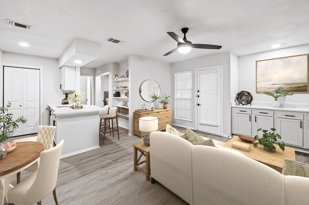 a living room and kitchen with white walls and a wooden floor  at Carmel at Deerfield, San Antonio, 78248