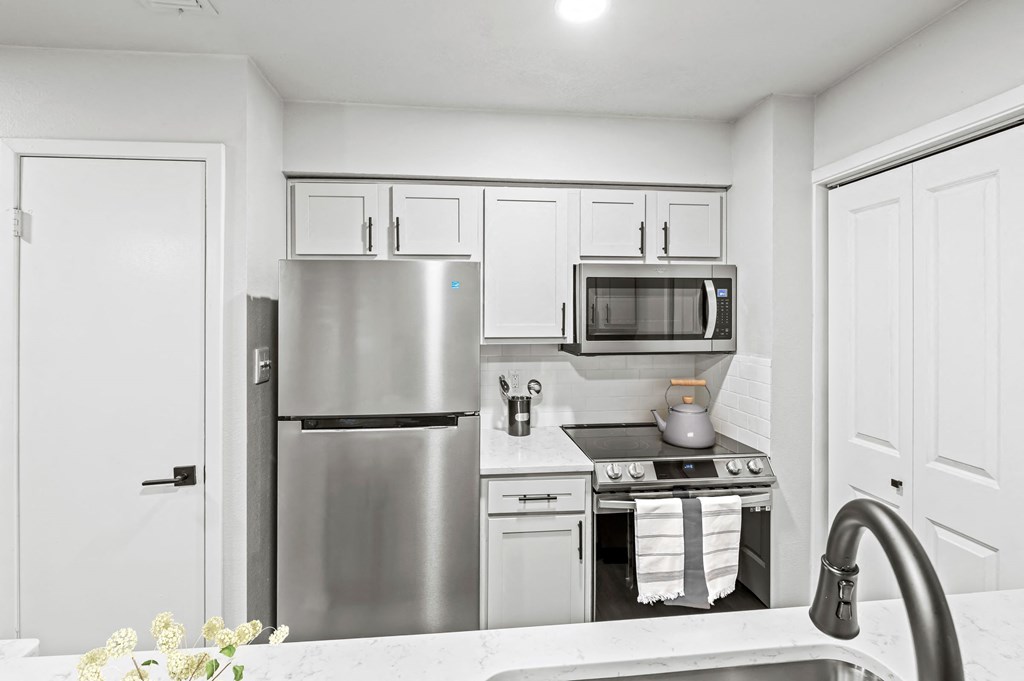 a kitchen with white cabinets and stainless steel appliances  at Carmel at Deerfield, San Antonio