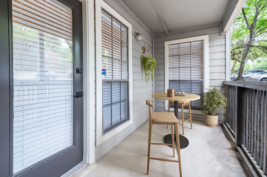 a small table and chair sit on a porch in front of a door  at Carmel at Deerfield, Texas, 78248
