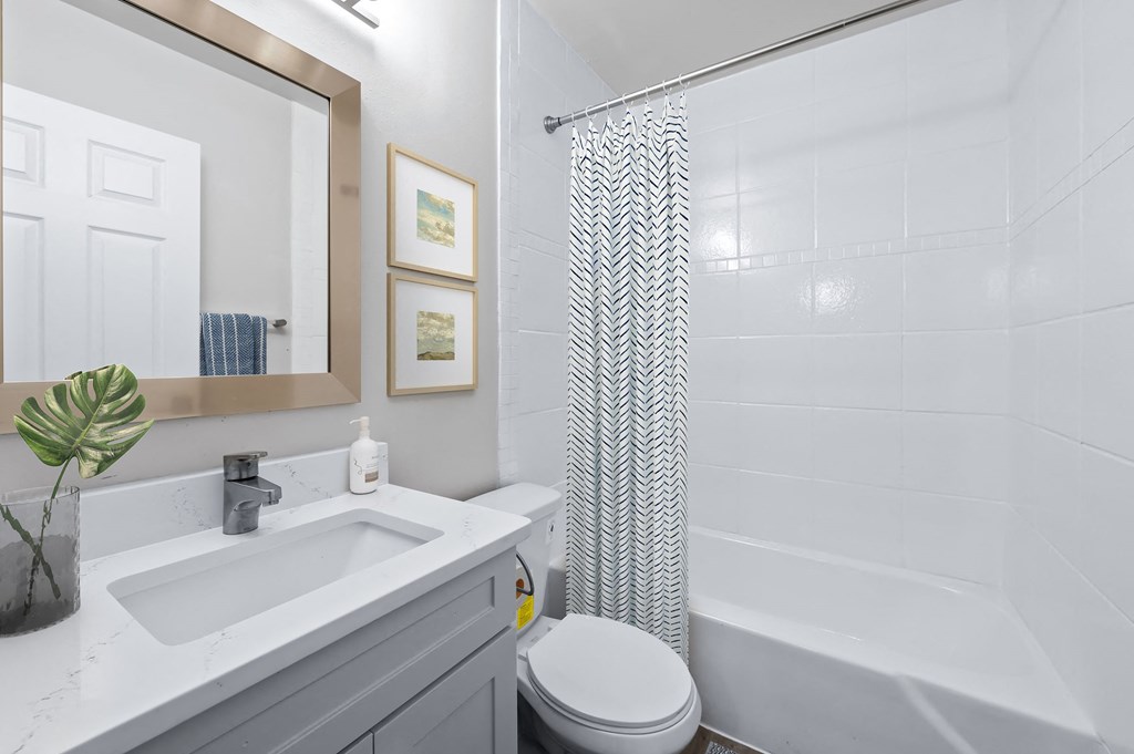 a bathroom with a white sink and toilet next to a white bathtub with a shower curtain  at Sunset Heights, Texas