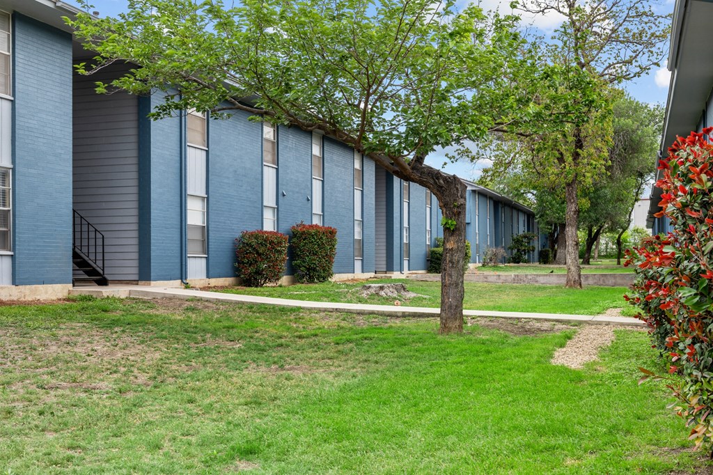 a building with blue siding and a tree in front of it  at Sunset Heights, San Antonio, TX