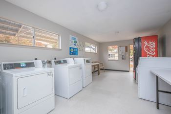 A laundry room with washers and dryers and a Coca-Cola fridge.