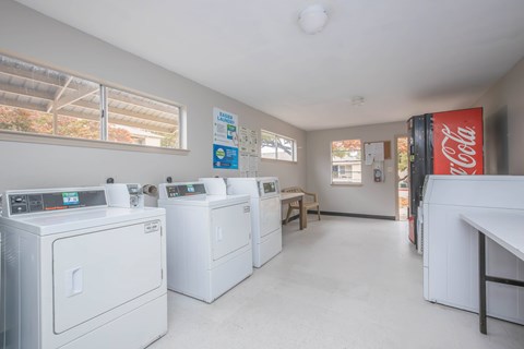 A laundry room with washers and dryers and a Coca-Cola fridge.
