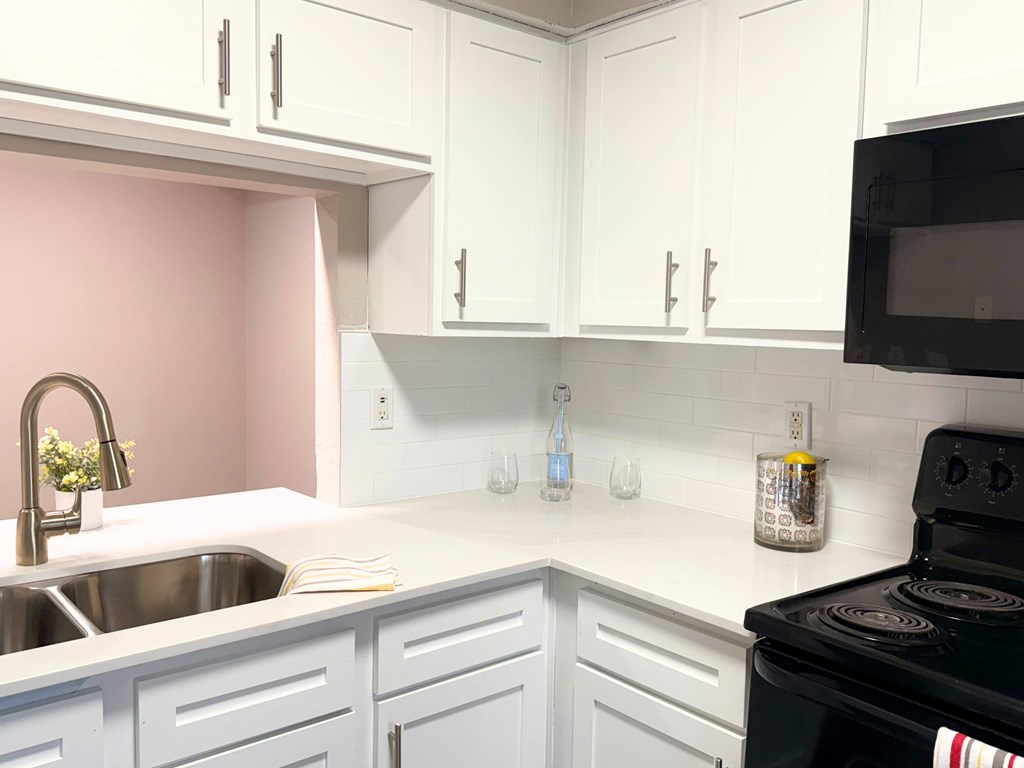 A kitchen with white cabinets and a black stove.