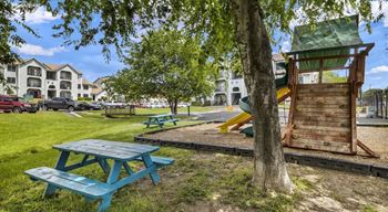 A playground with a wooden slide and picnic tables.