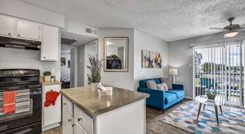 A kitchen with a black stove top oven and a blue couch.