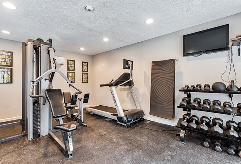 the gym has plenty of exercise equipment and a tv at The Broadwater at Salado Creek, San Antonio, Texas, 78216