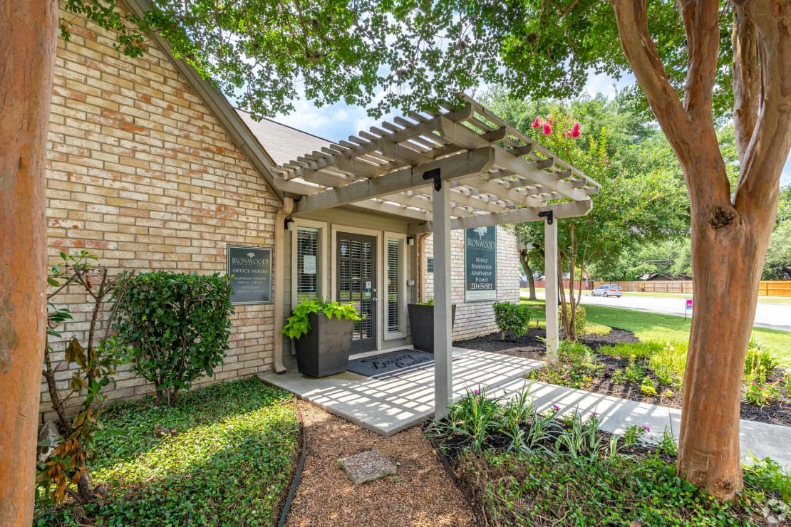 a patio with a pergola in front of a brick building