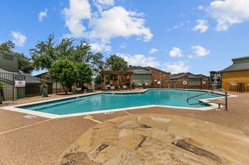 A large outdoor swimming pool surrounded by a stone patio.