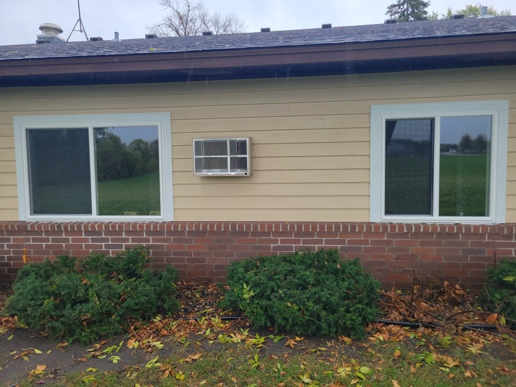 a home with two windows and a brick wall