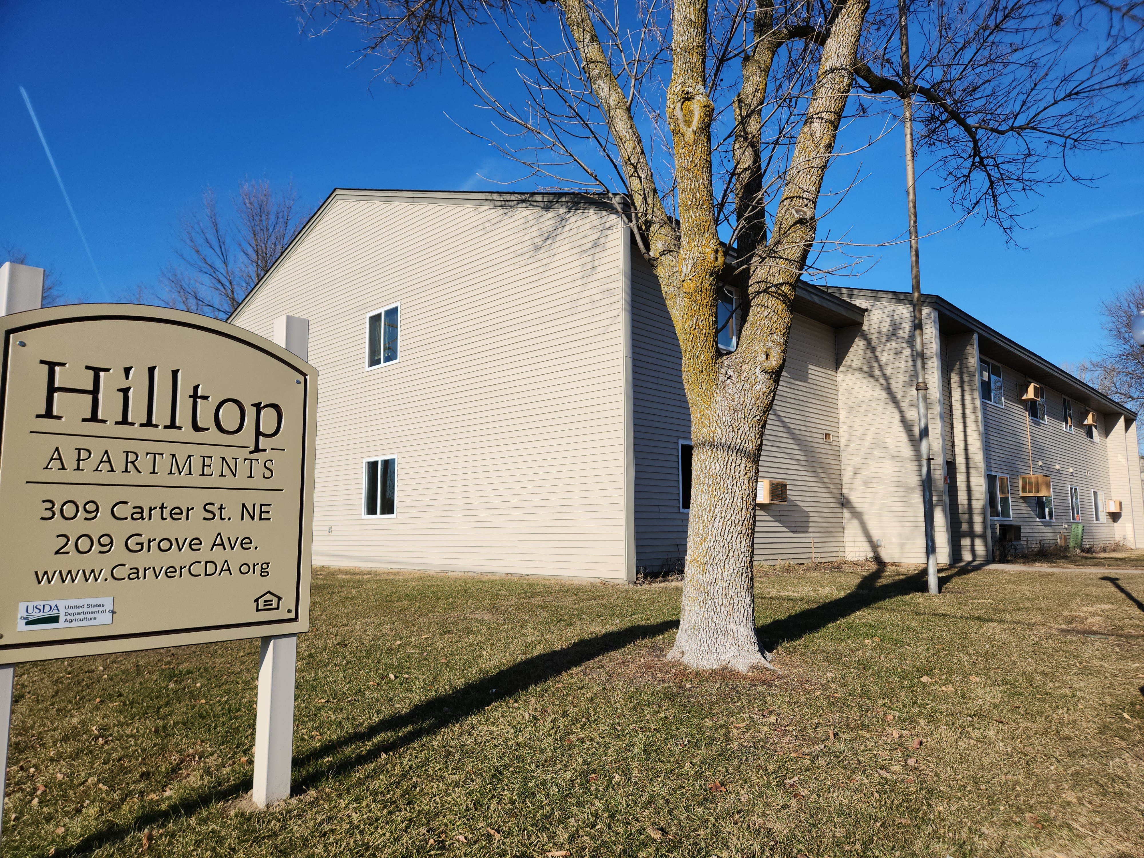 a white house with a sign in front of a tree