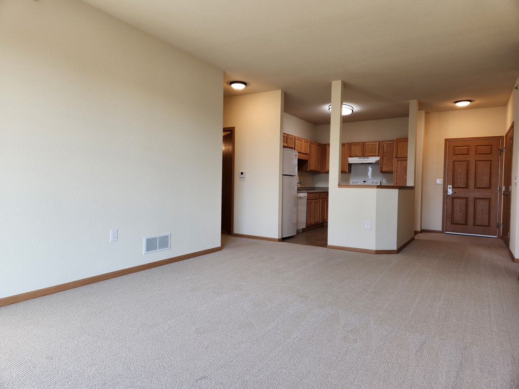 A spacious living room with a kitchen in the background.