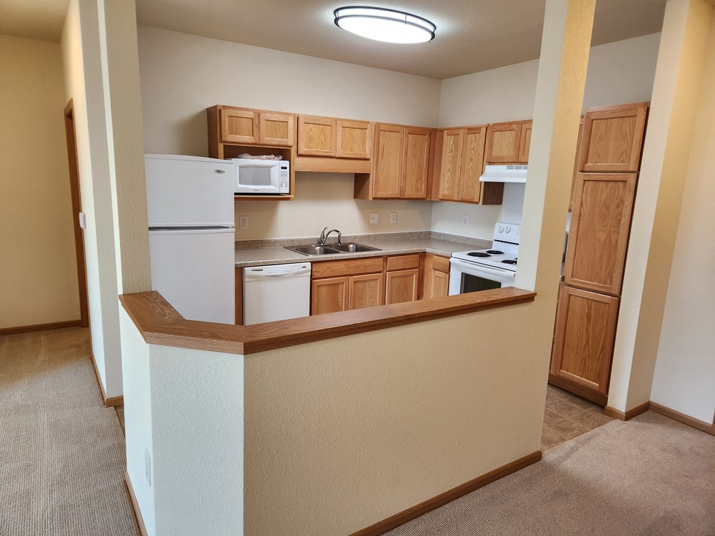 A kitchen with white appliances and wooden cabinets.