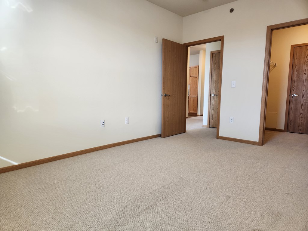 A room with carpeted floor and two doors.
