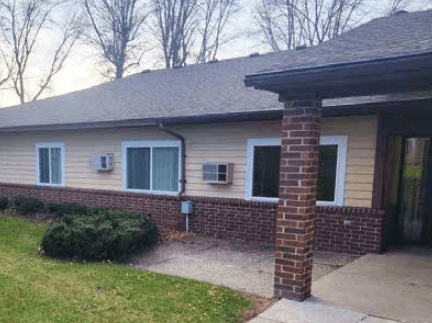 a brick house with green shutters and a sidewalk