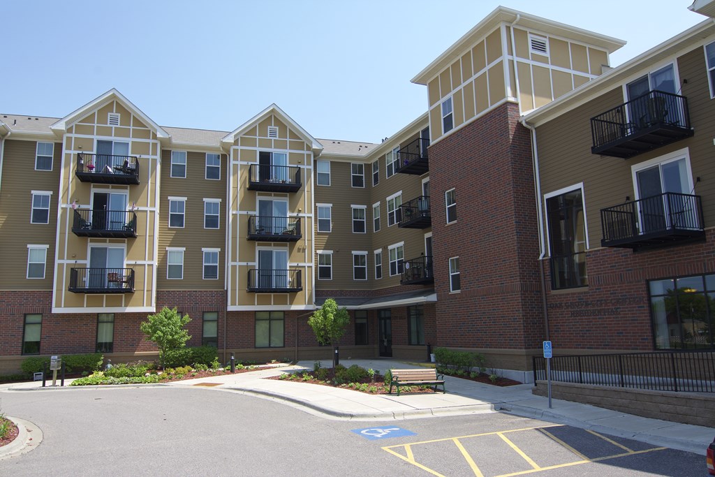Apartment complex with a parking lot in front.