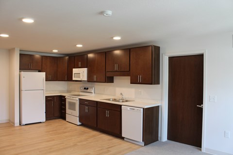 A kitchen with white appliances and brown cabinets.