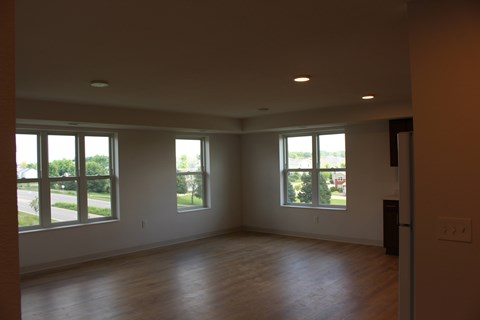 A large empty room with wooden floors and windows.